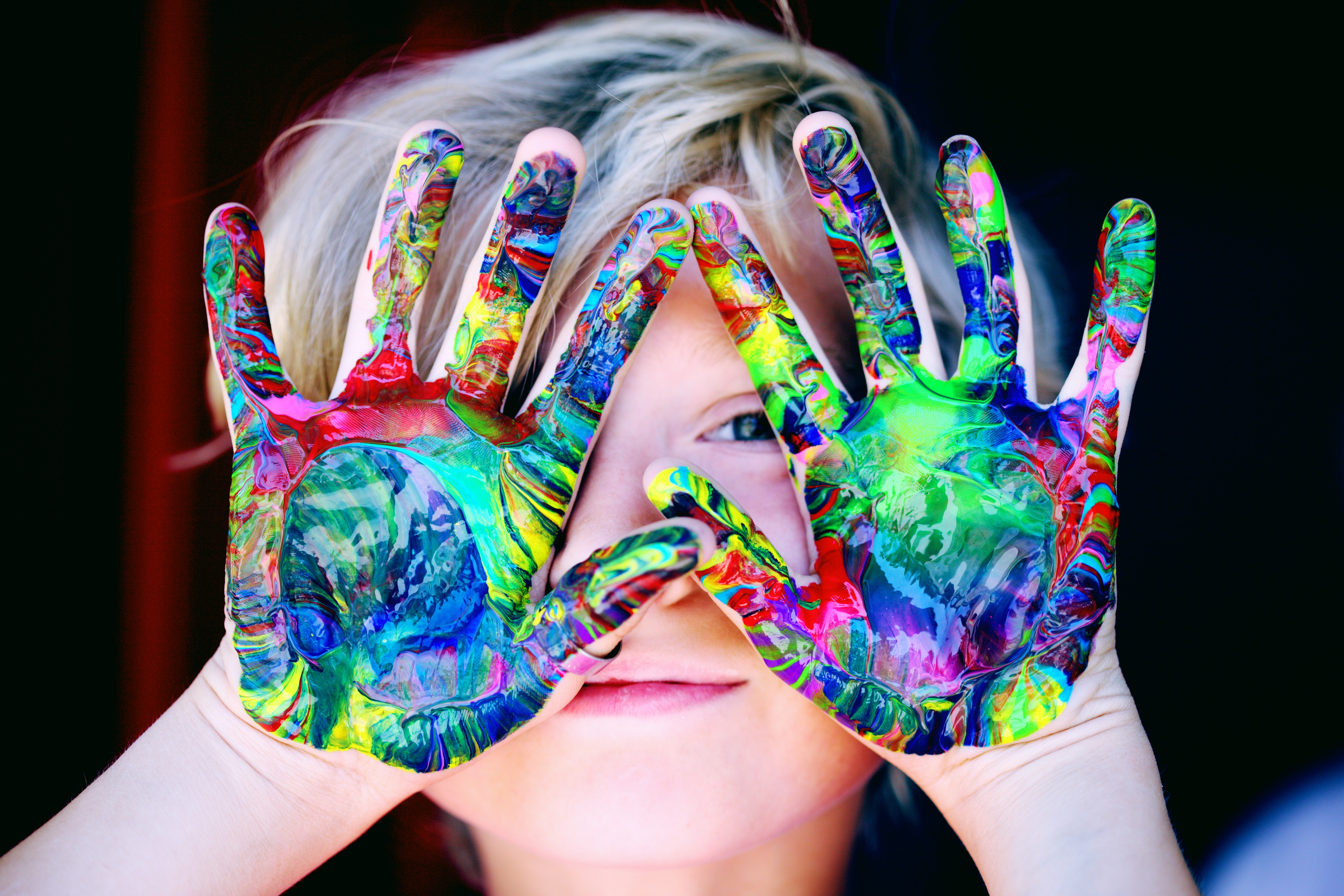 Boy with painted palms in fron tof his face