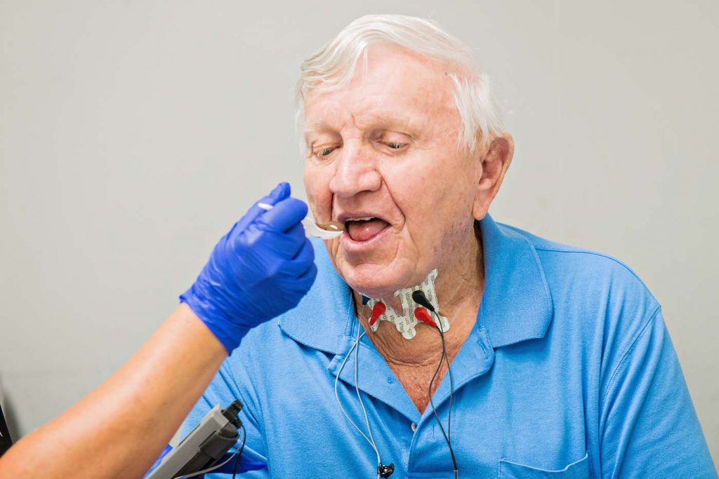 Therapist feeding an adult man during vital stim therapy for swallowing